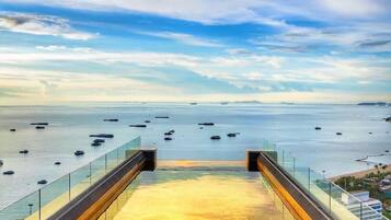 A glass-walled walkway leading to a beach with boats in the water.