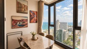 A dining area with a table and chairs, large windows with a city view, and artwork on the walls.