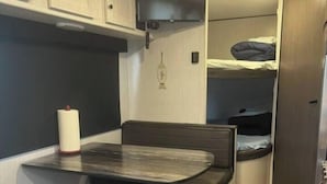 A compact kitchenette with a small table, bench seating, and a refrigerator. - Nice RV with AC in charming Holly Beach steps from the beach (Cameron)