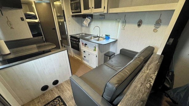 A compact RV interior with a kitchenette, a dining area, and a sleeping space. - Nice RV with AC in charming Holly Beach steps from the beach (Cameron)