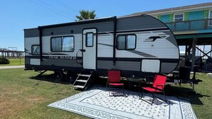 A travel trailer with a ramp and two red chairs on a patterned rug. - Nice RV with AC in charming Holly Beach steps from the beach (Cameron)