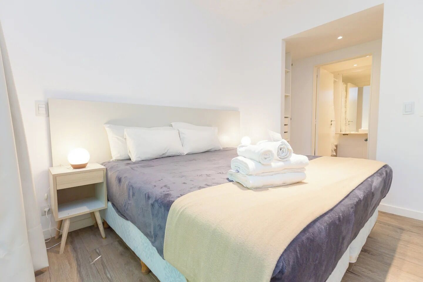 Una habitación de hotel moderna con una cama grande, una mesita de noche y un buró.