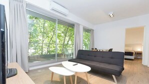 A modern living room with a sofa, a small table, and a TV. - Apartamento de 2 Ambientes en Belgrano (Buenos Aires)