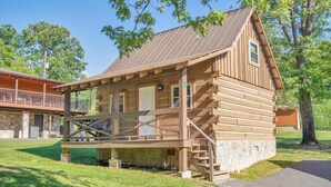 A rustic log cabin with a porch, a stone foundation, and a metal roof. - Cozy Log Cabin Retreat w/ Pool | Pigeon Forge TN (Pigeon Forge)