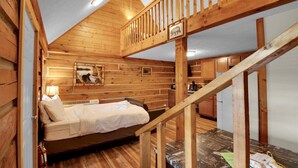 A wooden cabin interior with a loft bed, a small desk, and a dining area. - Cozy Log Cabin Retreat w/ Pool | Pigeon Forge TN (Pigeon Forge)
