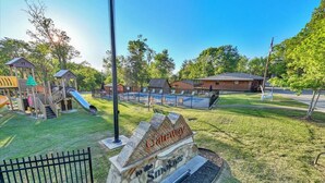 A playground with slides and climbing structures, a pool area with lounge chairs, and a sign that reads "Gateway to the Smokies". - Cozy Log Cabin Retreat w/ Pool | Pigeon Forge TN (Pigeon Forge)