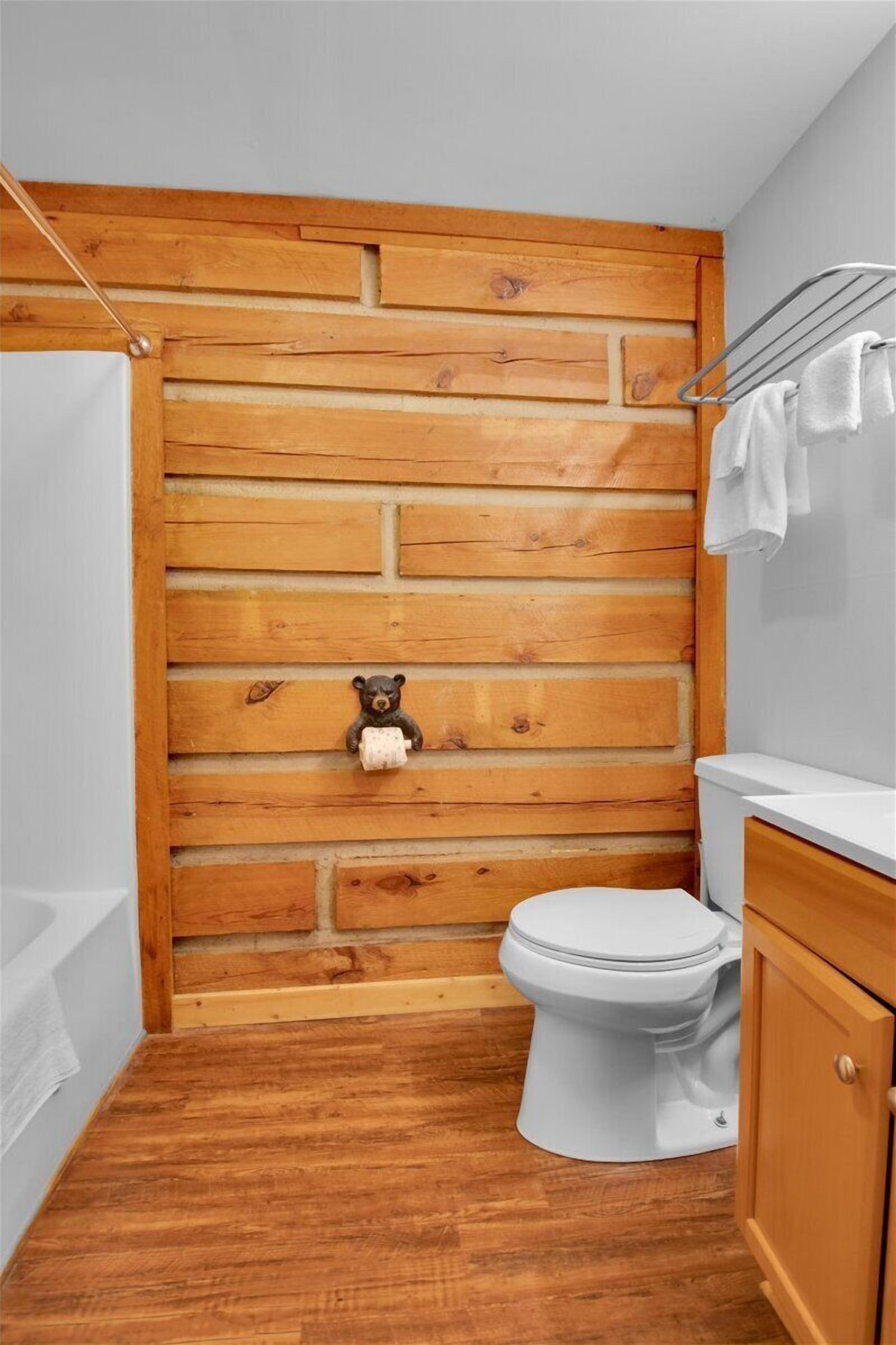 A bathroom with a wooden wall, a white toilet, a wooden cabinet, and a towel rack.