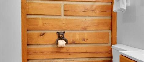 A bathroom with a wooden wall, a white toilet, a wooden cabinet, and a towel rack.