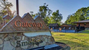 A stone sign with the words "Gateway to the Smokies" and a wooden structure resembling a roof. - Charming 1BR Smoky Mtn Cabin w/ Pool Access (Pigeon Forge)