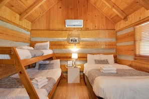 Una habitación tipo cabaña con literas, un cuadro en la pared y una mesita de noche con una lámpara.
