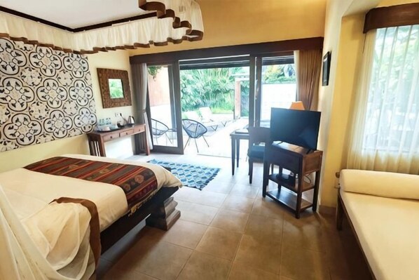 A bedroom with a bed, a desk, a TV, and a sofa.