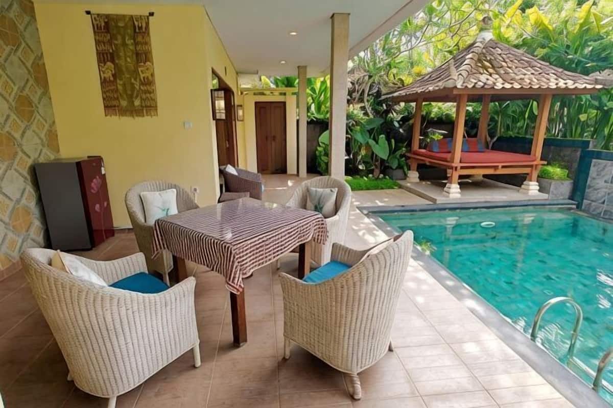 A pool area with wicker furniture, a gazebo, and a view of the pool.