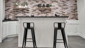 A kitchen with a brick backsplash, a bar area with two stools, and white cabinetry.