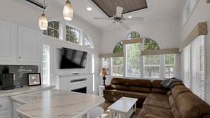 A spacious living area with a kitchen, a large brown sectional sofa, a flat-screen TV, and a ceiling fan. - Charming 1BR Cottage with Loft near Dollywood (Pigeon Forge)