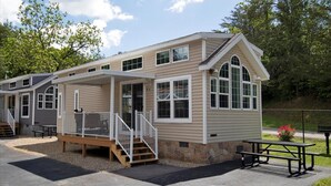 A two-story building with a porch, a staircase, and a picnic table. - Charming 1BR Cottage with Loft near Dollywood (Pigeon Forge)