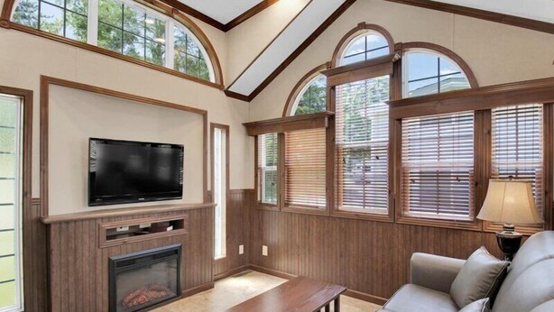 A living room with a fireplace, television, and large windows. - 1BR Cottage Retreat with Loft near Dollywood (Pigeon Forge)
