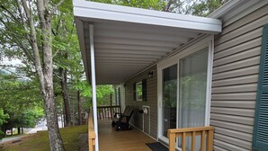 A covered porch with a wooden deck, a bench, and a door leading to a glass door. - Pigeon Forge 2BR Cottage w/ King & Queen Beds (Pigeon Forge)