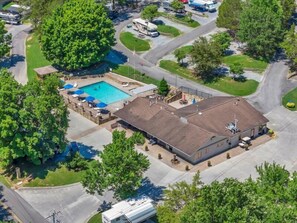 An aerial view of a property with a swimming pool, a covered patio, and a building with a flat roof.