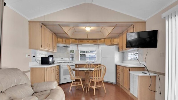 Un espacio habitable pequeño con kitchenette, comedor y sofá.