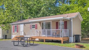 Ein Bungalow mit Veranda, Picknicktisch und einer kleinen Terrasse.