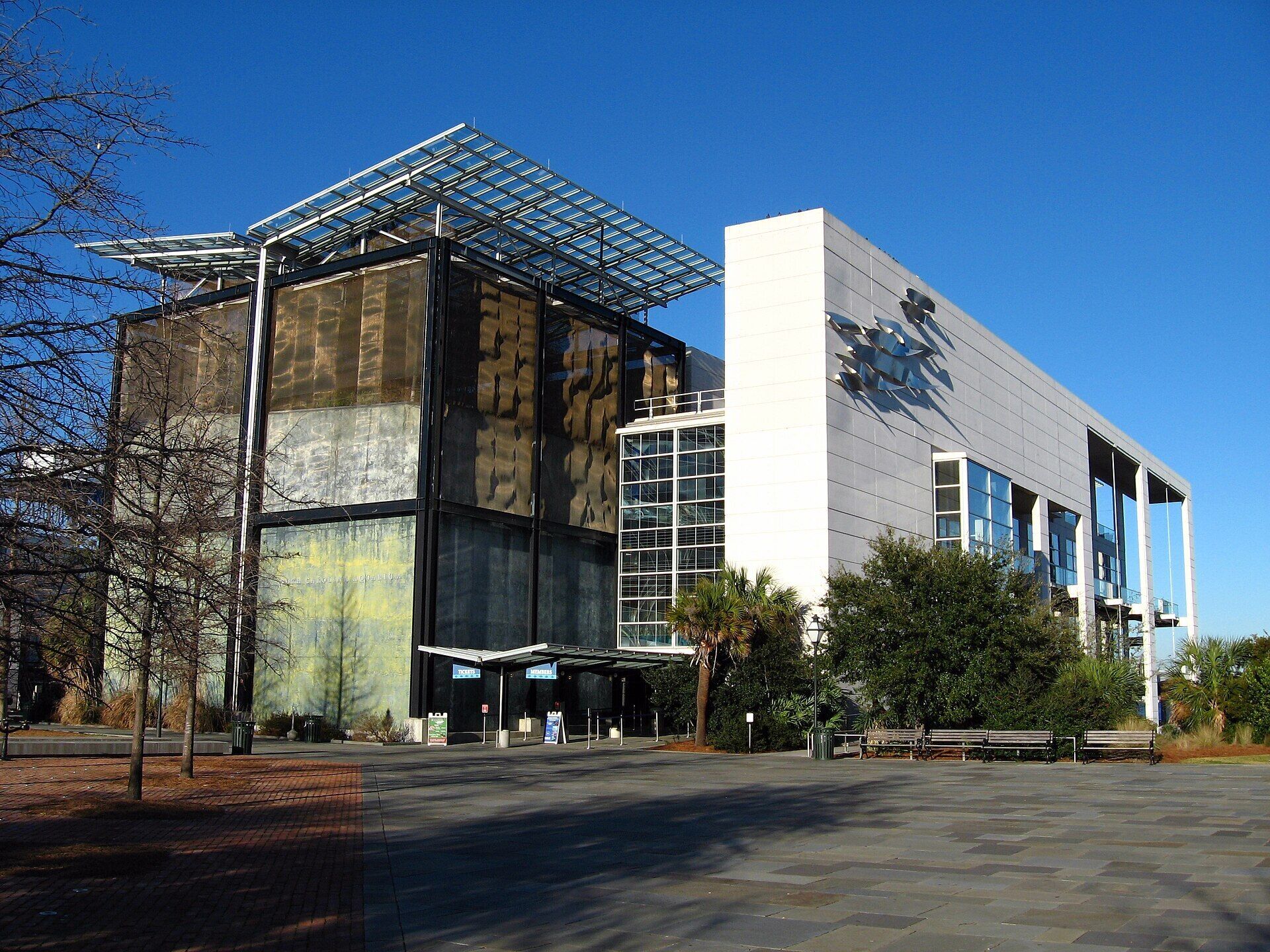 A modern building with a glass facade, a flat roof, and a large entrance area.
