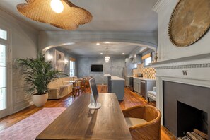 Ein geräumiges Wohnzimmer mit einem Holzessttisch, bequemen Sitzmöglichkeiten, einer großen Küstpflanze und einem Kamin.