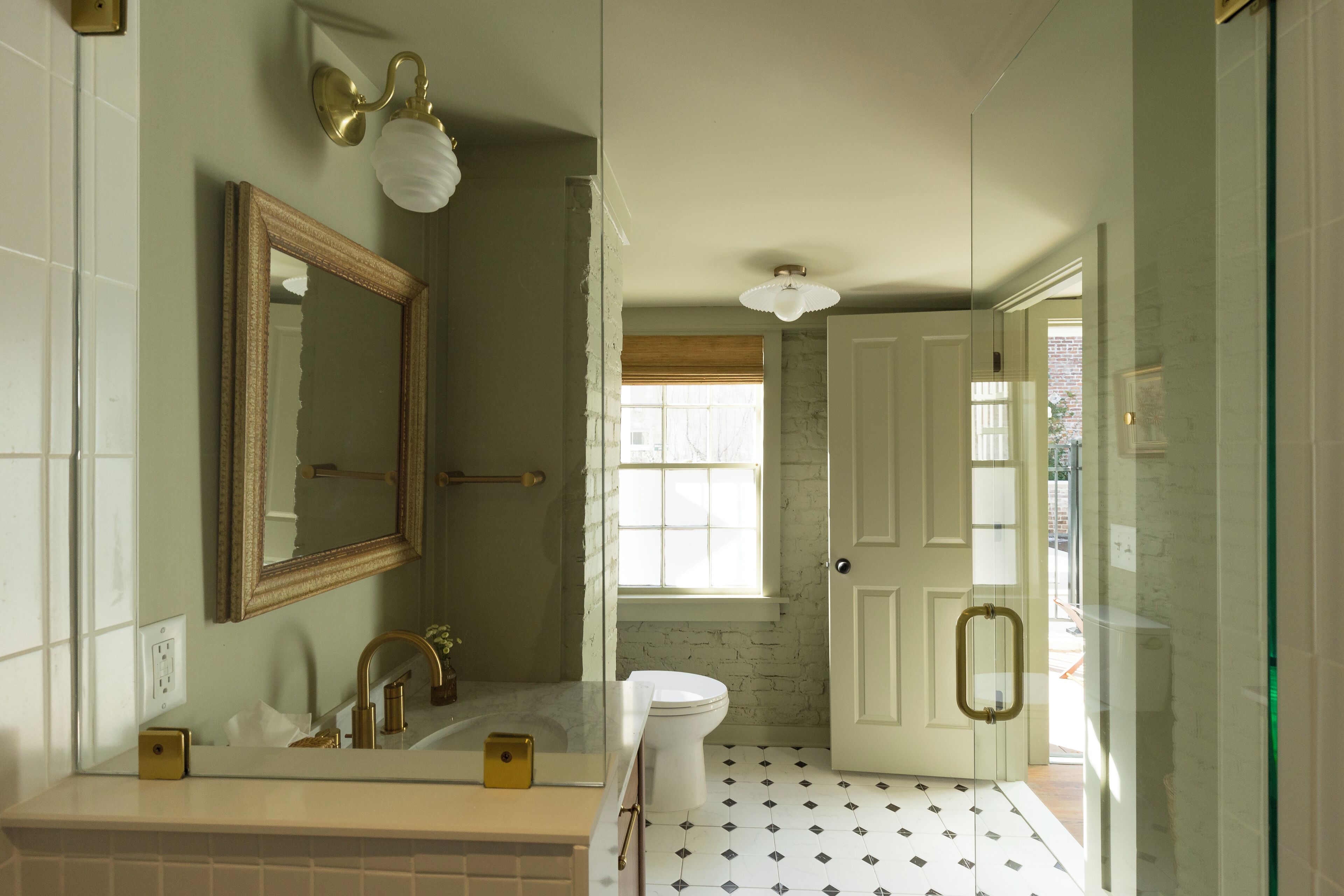 A bathroom with a large mirror, a sink, a toilet, and a shower area.