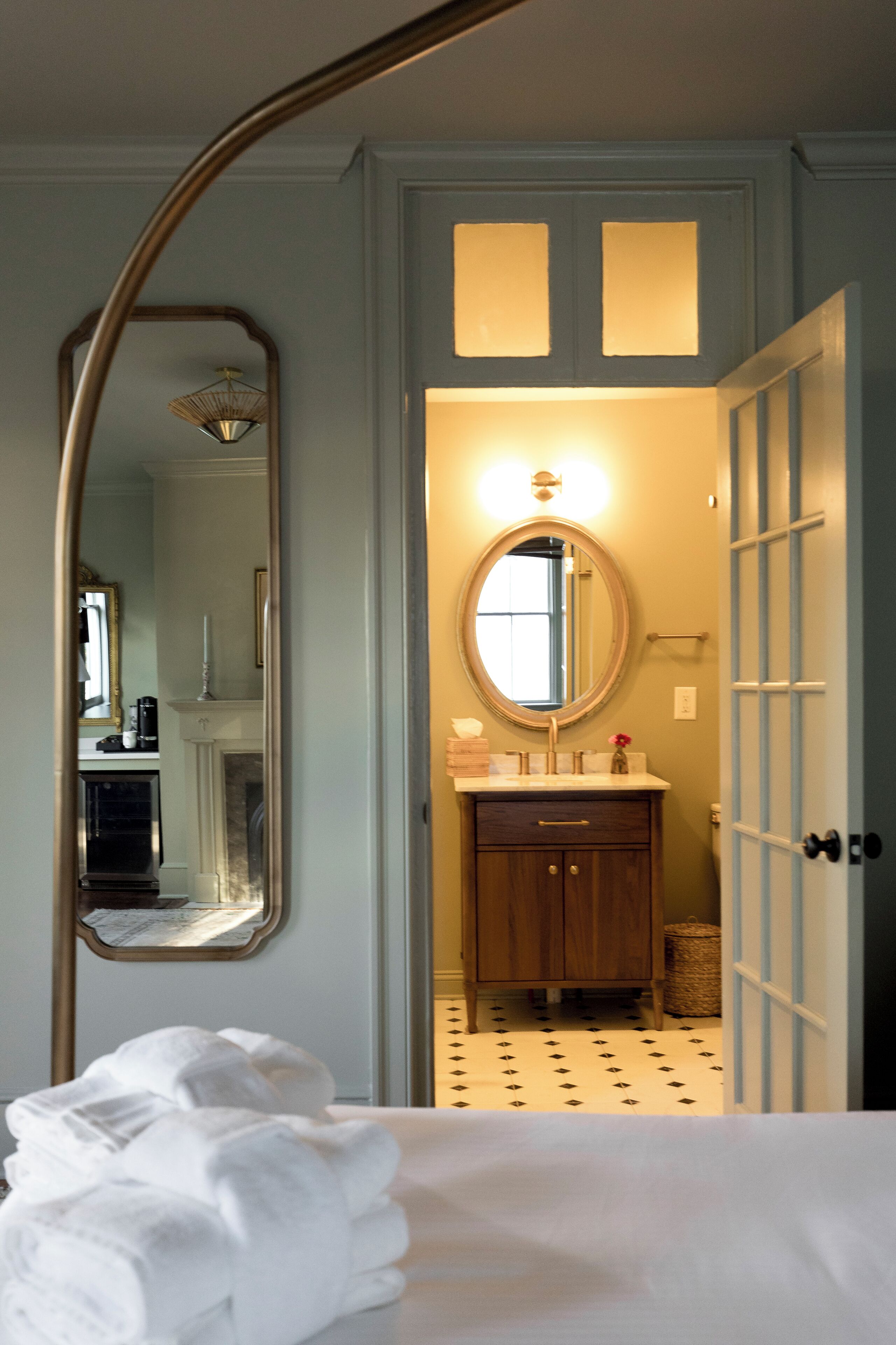 Una habitación de hotel con una cama, un baño con espejo, lavamanos y puerta.