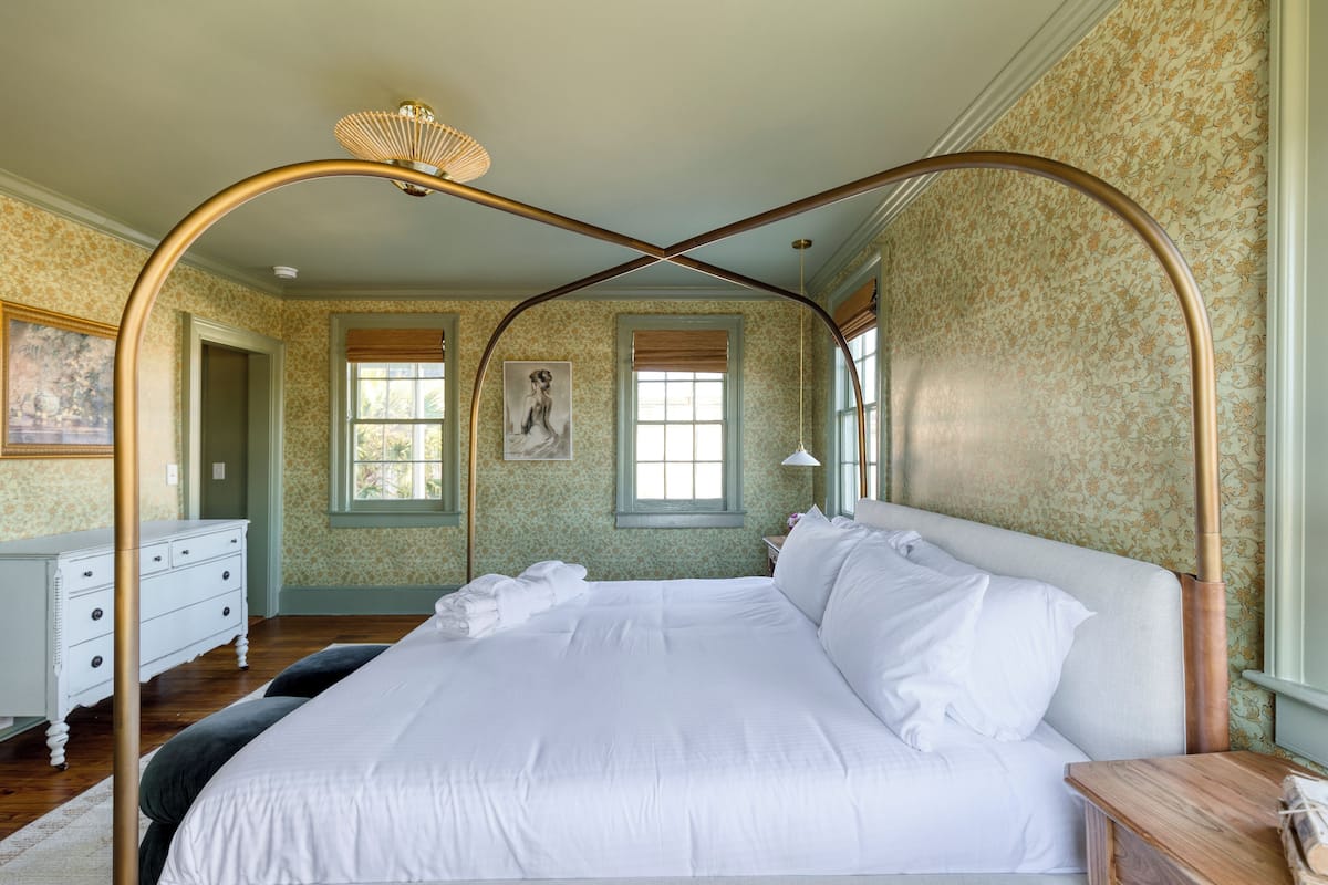 A bedroom with a four-poster bed, a wooden nightstand, and a white dresser.