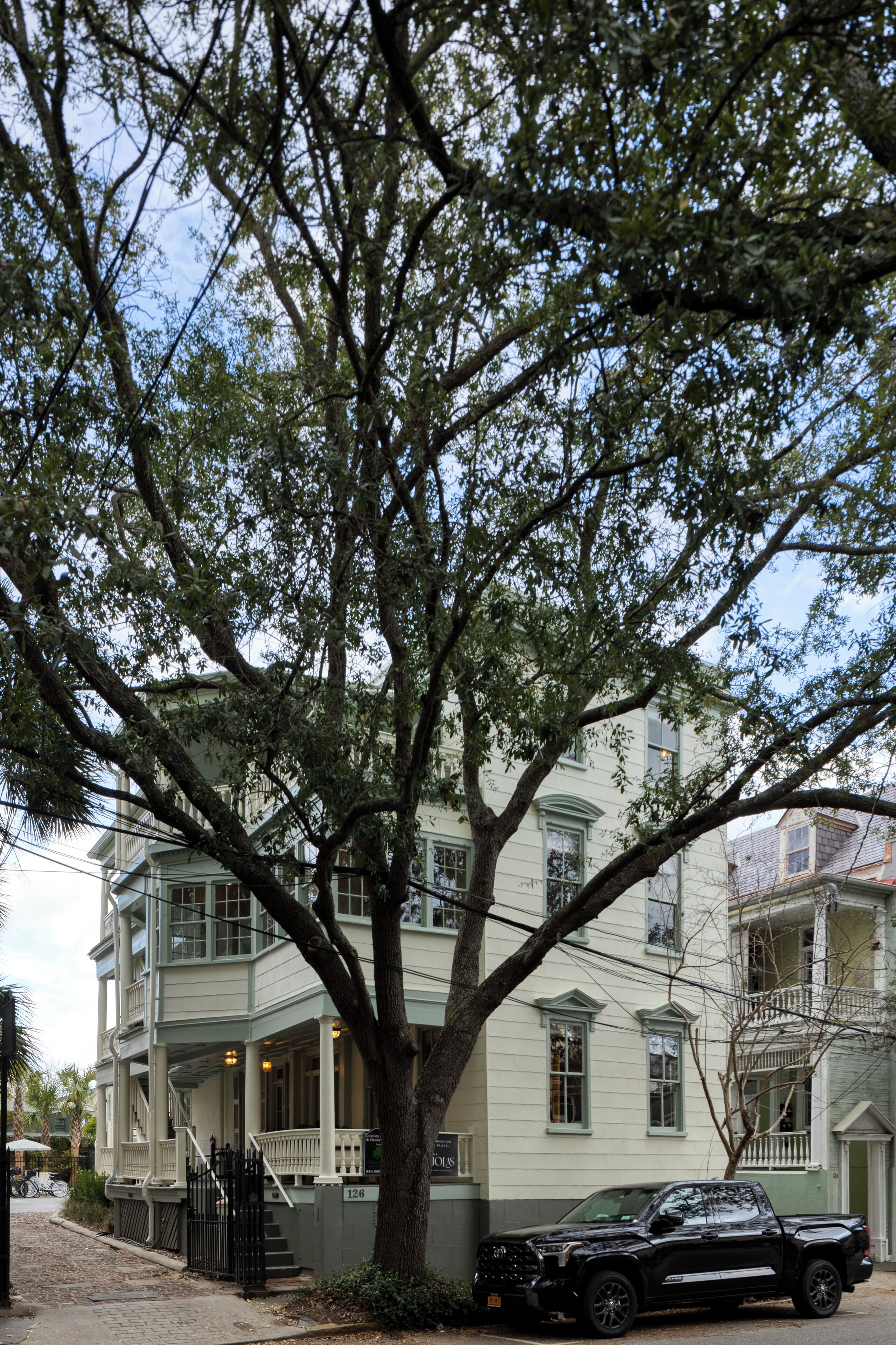 A two-story building with a large tree in front.