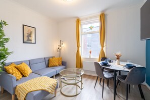 Relax in this inviting living space with a sofa, dining table, and potted plant.