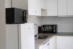 Kitchen area with a refrigerator, microwave, toaster oven, and sink.