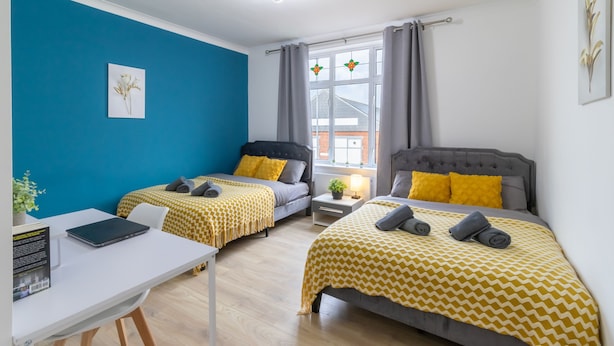 A room with two beds, a desk, and a window with curtains.