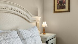 A neatly made bed with patterned pillows, a white headboard, a bedside table with a lamp, and a framed picture on the wall. - Hidden Palms! Next to Shipwreck Island! (Panama City Beach)