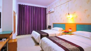 A hotel room with two beds, a desk, and a television.