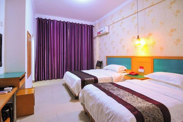 A hotel room with two beds, a desk, and a television.