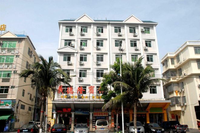 Un hotel de varios pisos con fachada plana, unidades de aire acondicionado y una entrada a nivel de calle con señalización.
