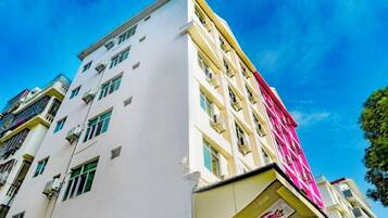 Un immeuble à plusieurs étages, doté d’une façade blanche et d’un auvent rose.
