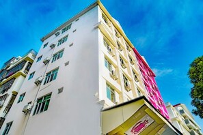 A multi-story building with a white facade and a pink awning. - Yidelong Hotel (Sanya)