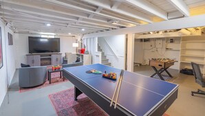Une pièce spacieuse équipée d’une table de ping-pong, d’un baby-foot et d’un téléviseur.