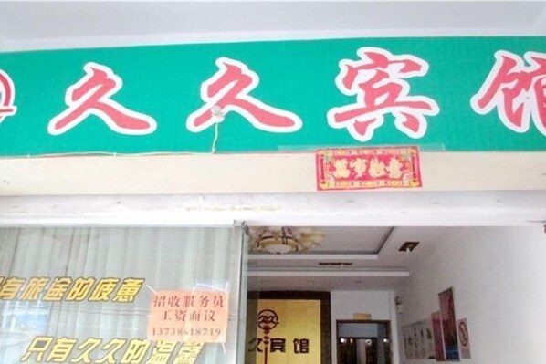 Entrada de hotel com uma placa verde exibindo caracteres chineses.