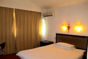 A hotel room with a bed, curtains, an air conditioning unit, and wall-mounted lights. - Taizhou Jiujiu Hotel (Taizhou)