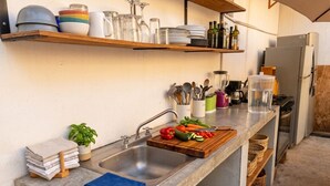 Una cocina con un lavamanos, encimera y varios utensilios.