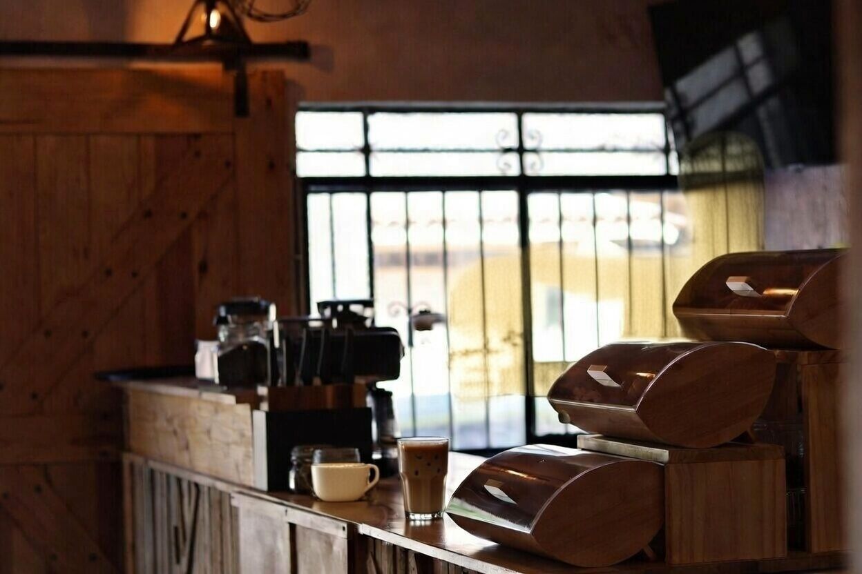 A rustic wooden interior with a coffee machine, a cup of coffee, and a glass of iced coffee on a counter.