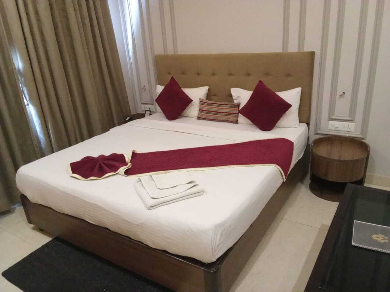 Una cama bien hecha con un edredón blanco, almohadas rojas y una manta roja.