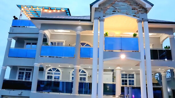 A multi-story hotel with balconies, large windows, and a covered outdoor area. - 4BR Villa Pvt Pool, Rooftop. 10m walk to Beach. Starlink. Free Airport pick up  (Accra)