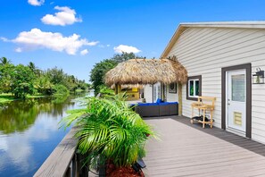 A waterfront property with a thatched-roof structure, a wooden deck, and a view of a calm river. - Waterfront Oasis, 5B, 4B, Jacuzzi, sleeps 12 (Atlantis)