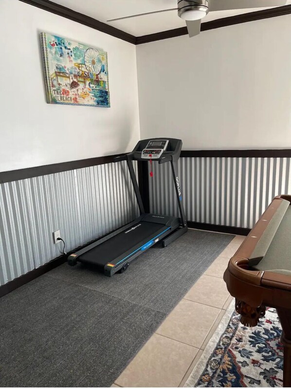 Une pièce avec un tapis de course, un tapis à motifs et un tableau accroché au mur.