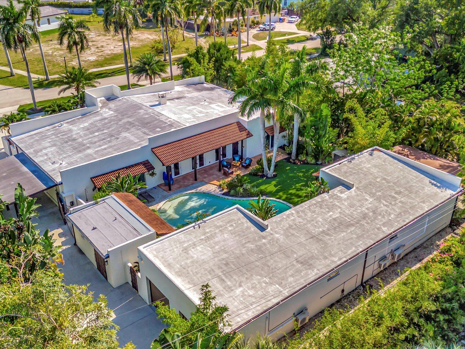 A modern house with a swimming pool, surrounded by palm trees and a well-maintained lawn.