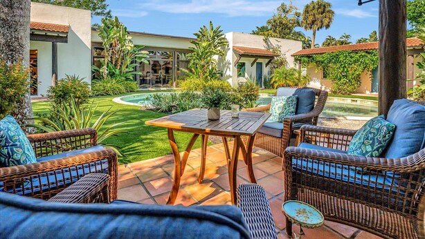 A patio with wicker furniture, a pool, and a view of a modern house. - Sedona Style Resort home awaits your company! (Fort Myers)